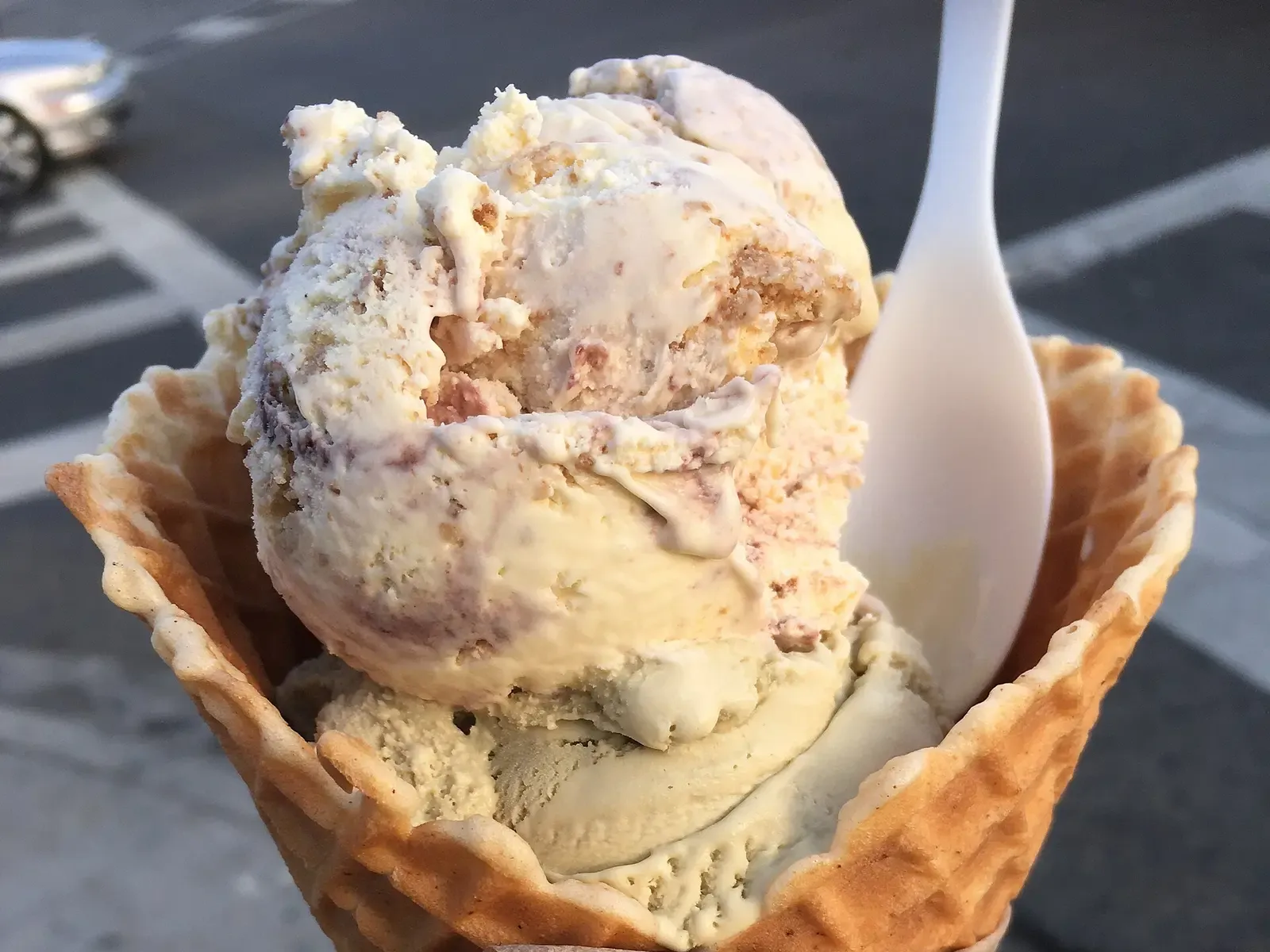 Two scoops of ice cream in a waffle cone with a plastic spoon. The photo was not taken at a Germantown shop.