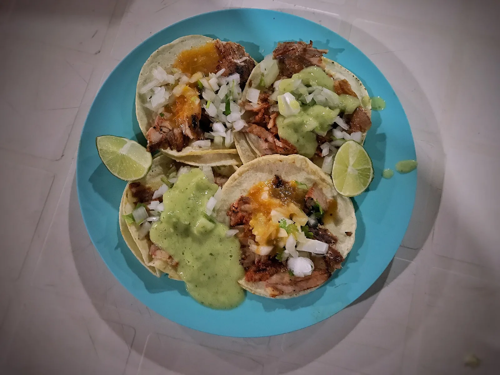 Al pastor tacos with onion, cilantro, salsa and lime on a blue plate. The photo was not taken at a Germantown restaurant.