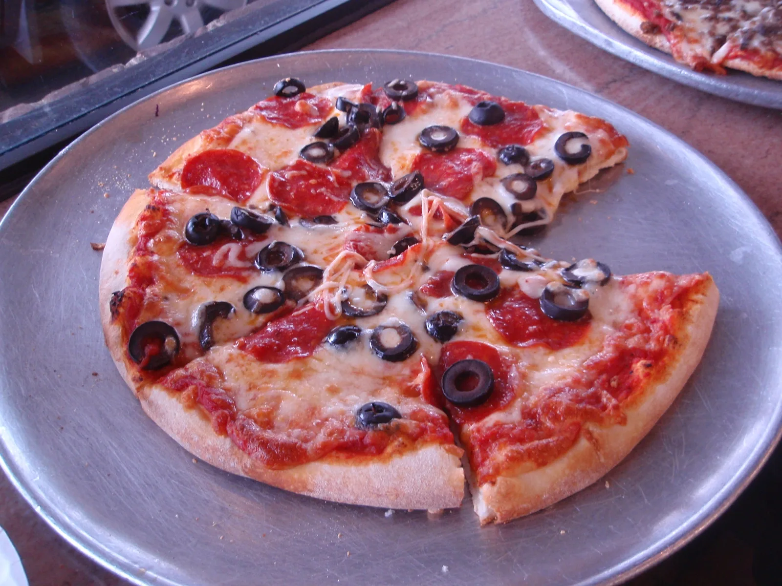 A pepperoni and black olive pizza on a metal tray. The photo was not taken at a Germantown restaurant.